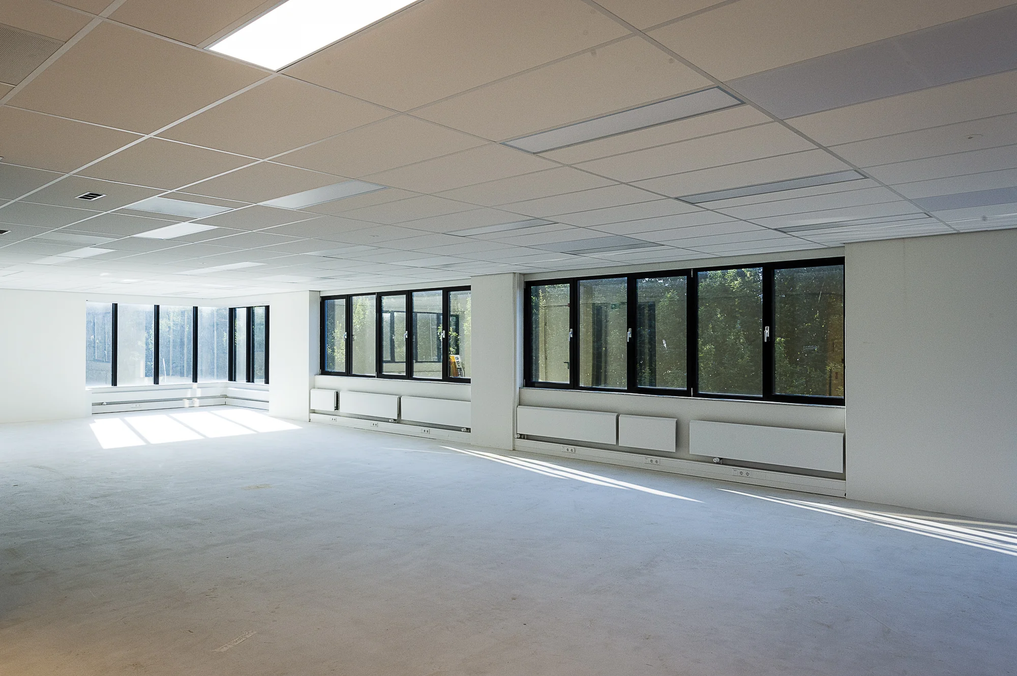 Lichte, lege kantoorruimte aan de Max Euwelaan met grote ramen en systeemplafond.